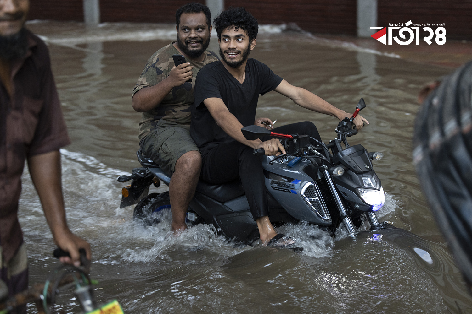 কোমর পানিতে মোটরসাইকেল হাস্যোজ্জ্বল চালক ও আরোহী/  ছবি: নূর-এ-আলম