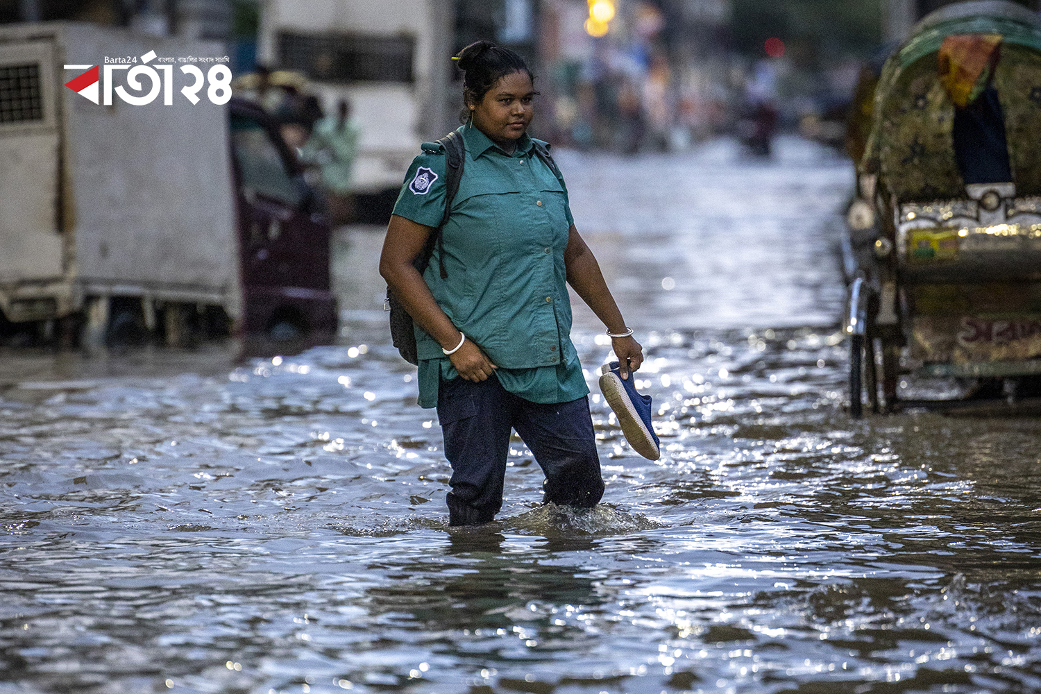 ডুবন্ত রাস্তা জুতা খুলে কর্মস্থলে যাচ্ছেন এক নারী পুলিশ সদস্য/ ছবি:নূর-এ-আলম